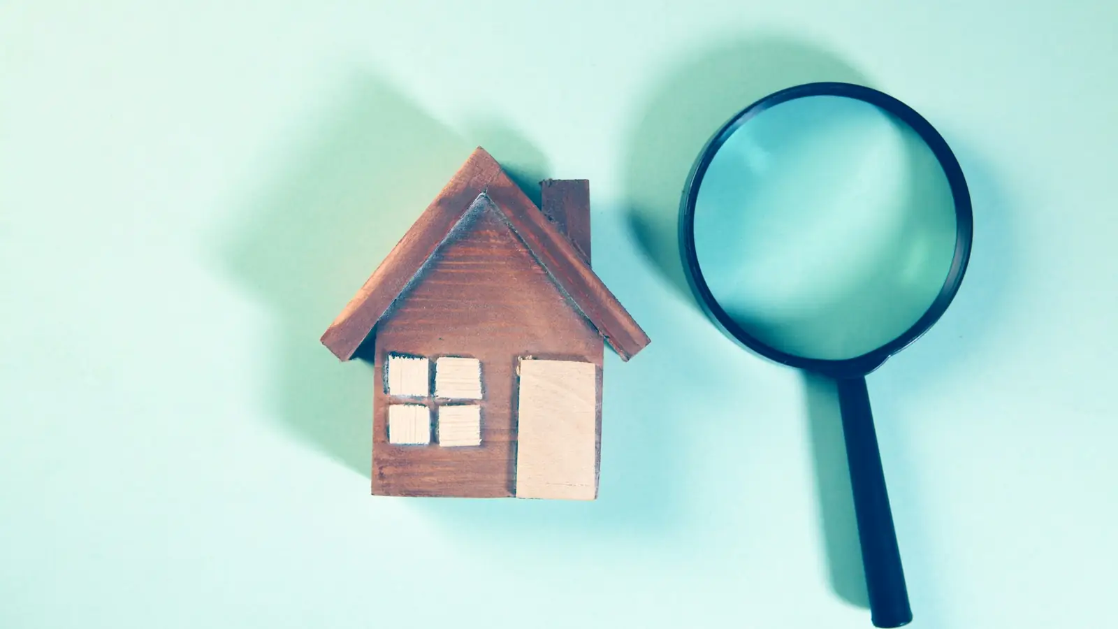 Loupe posée sur une maquette de maison en bois