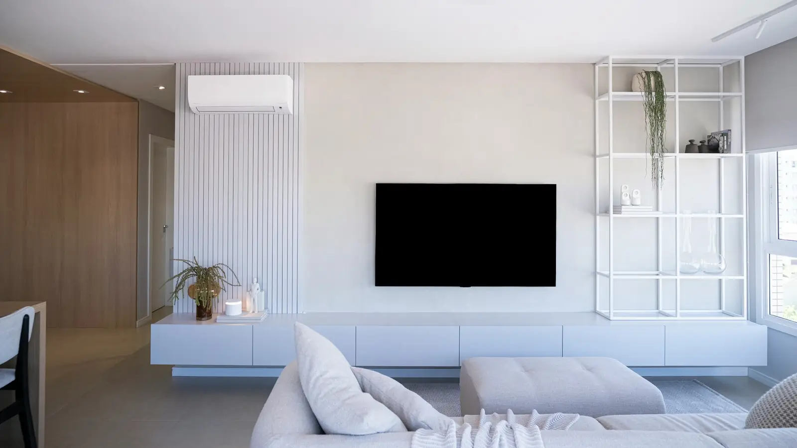 Salon blanc lumineux équipé d’un climatiseur mural