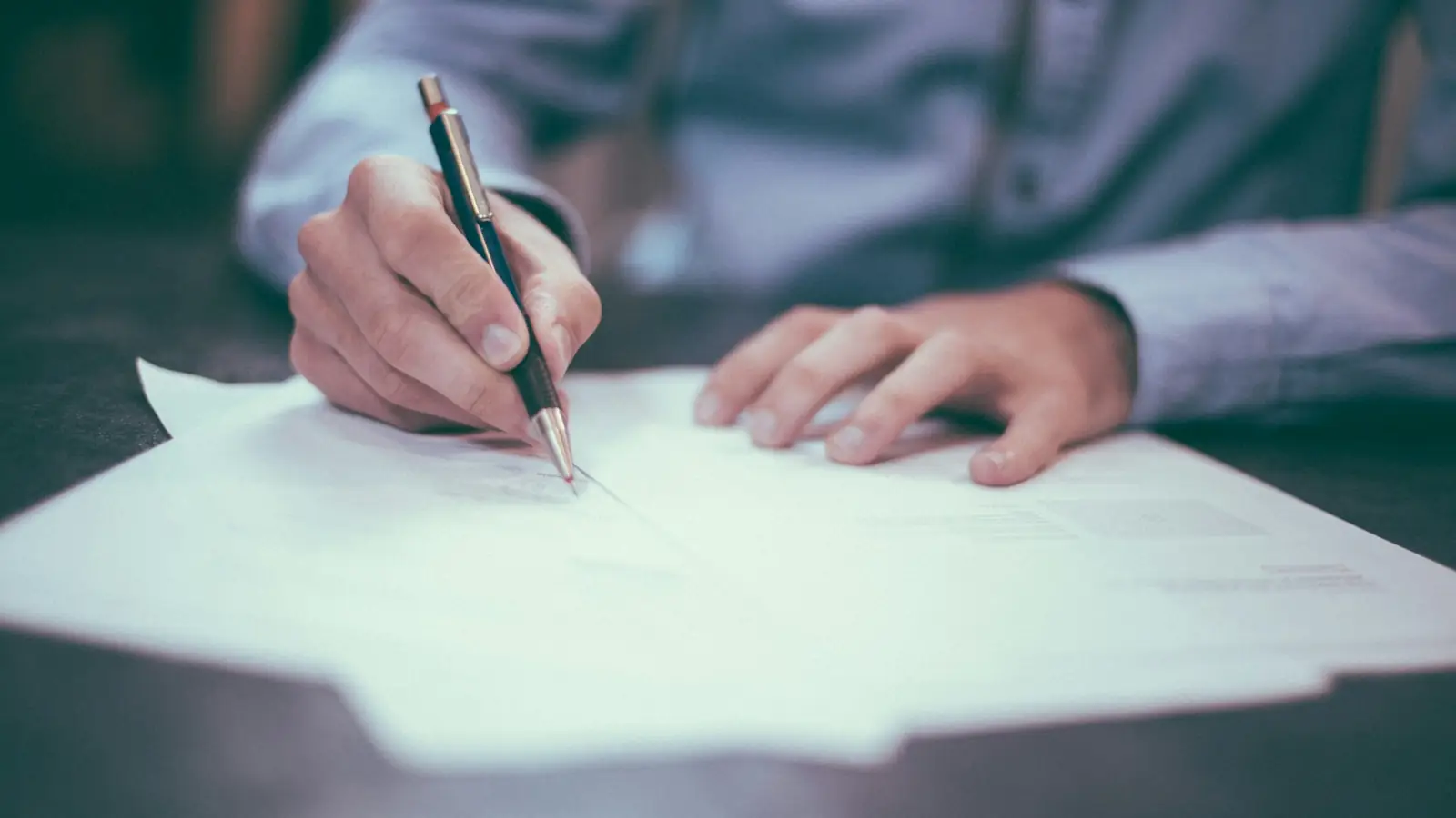Main signant un document de prêt sur un bureau
