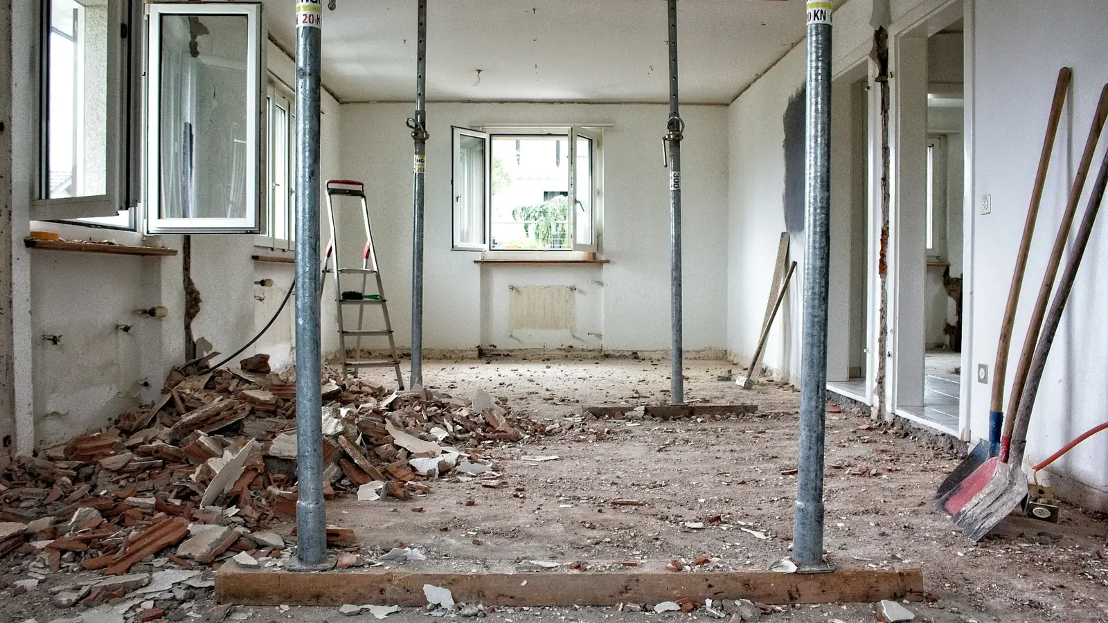 Pièce en rénovation baignée de lumière avec étais métalliques