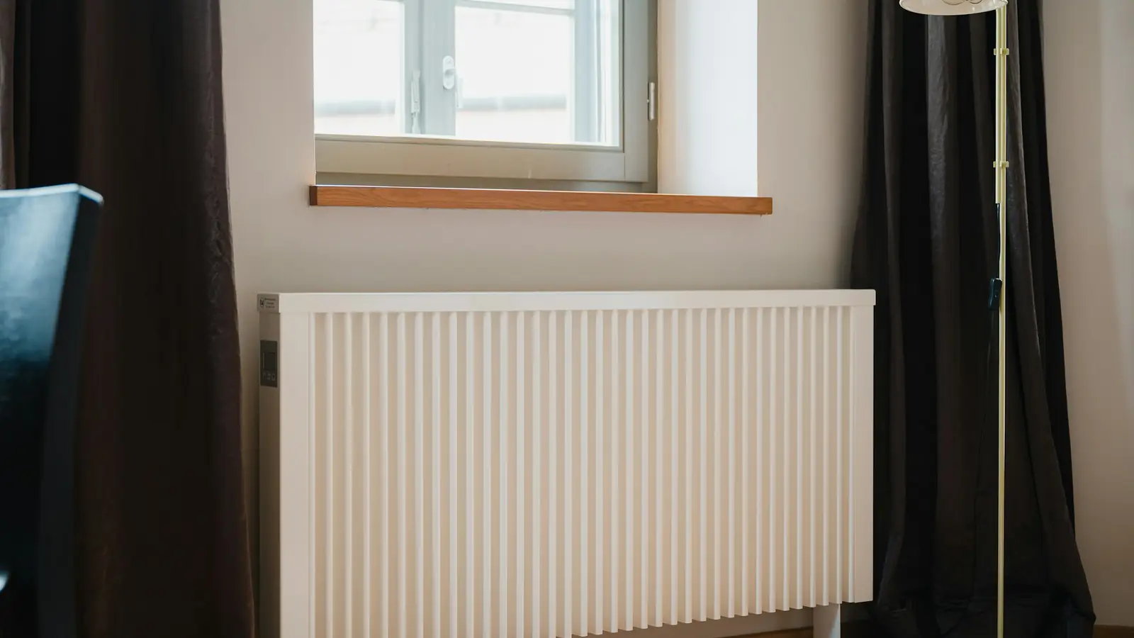 Radiateur électrique blanc fixé sous une fenêtre