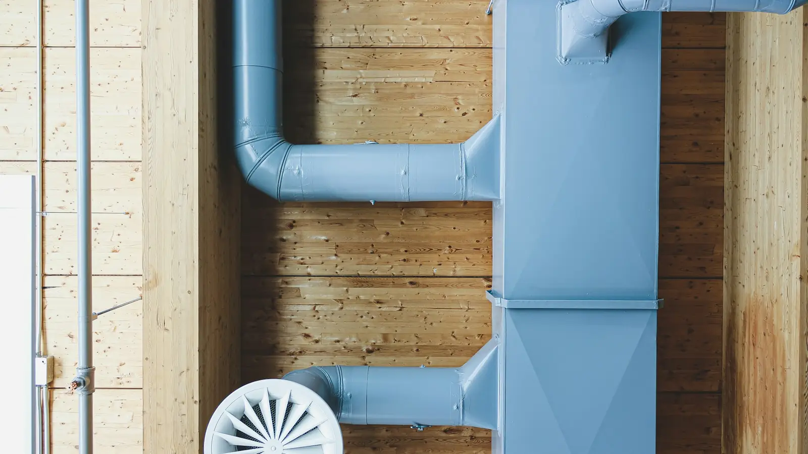 Gaines de ventilation et bouche d’insufflation posées sur un mur en bois