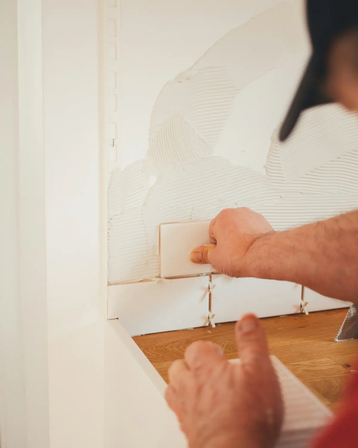 Artisan posant un carrelage mural dans une cuisine